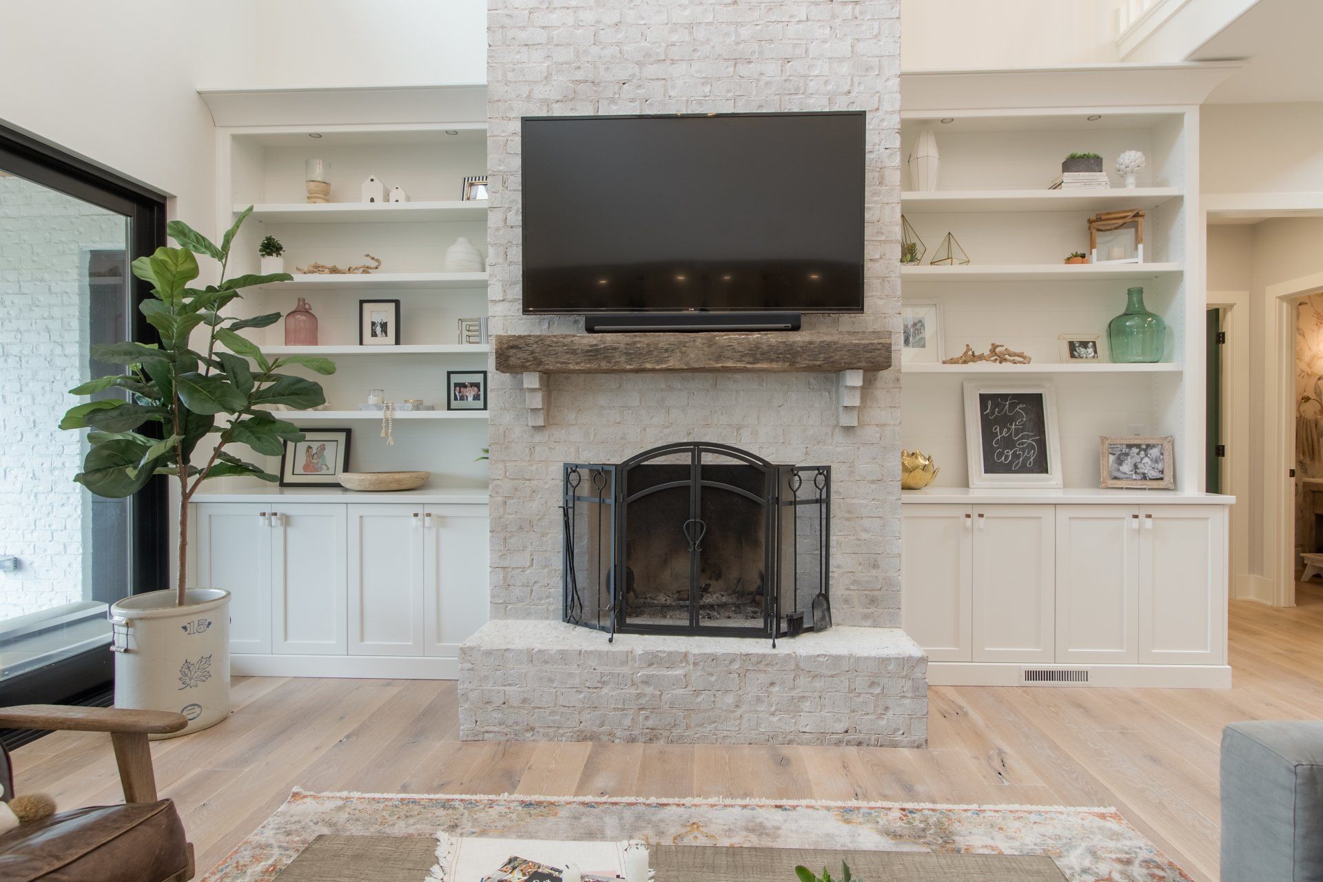 A living room with a fireplace and a flat screen tv on the wall.