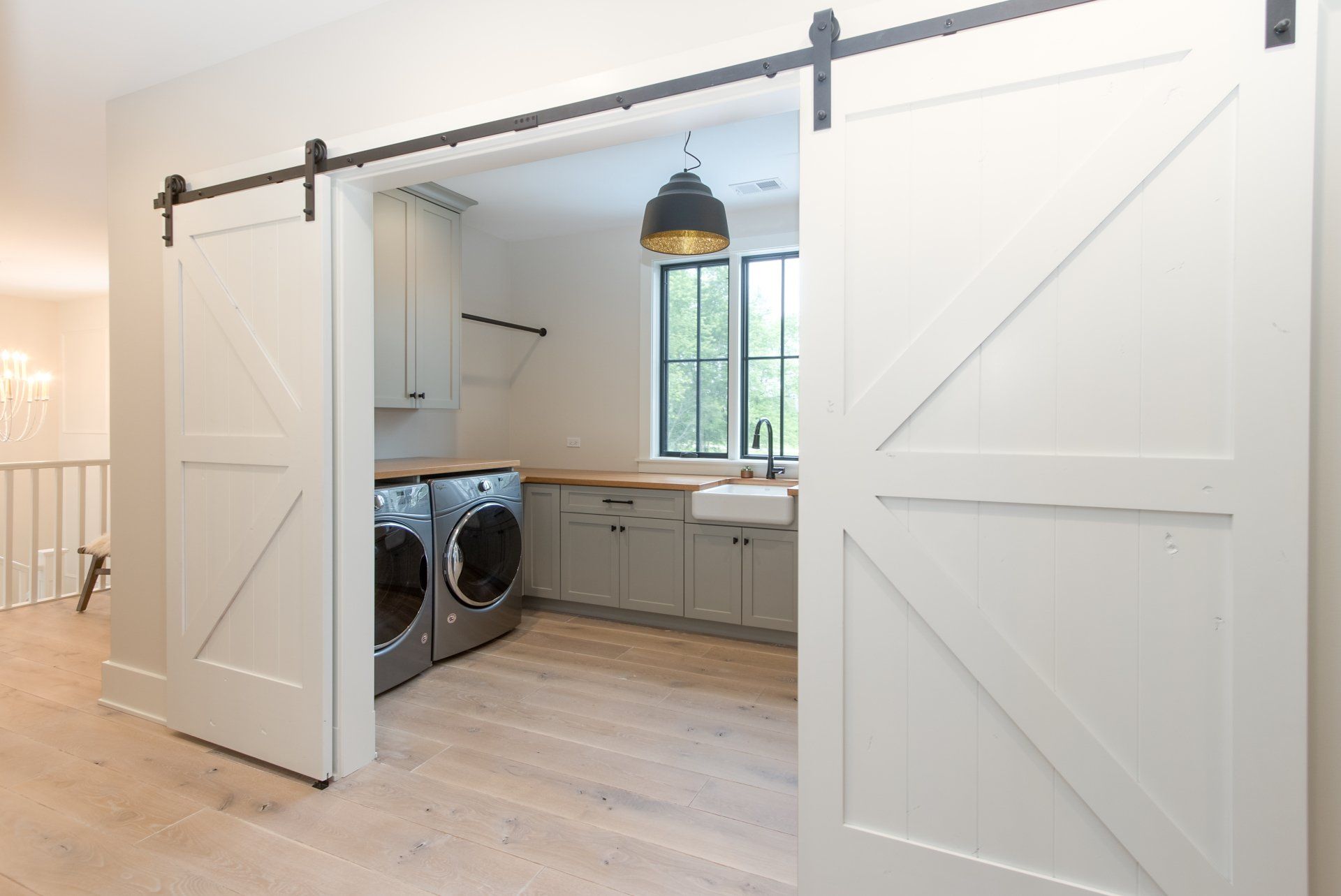 A laundry room with a washer and dryer and sliding barn doors.