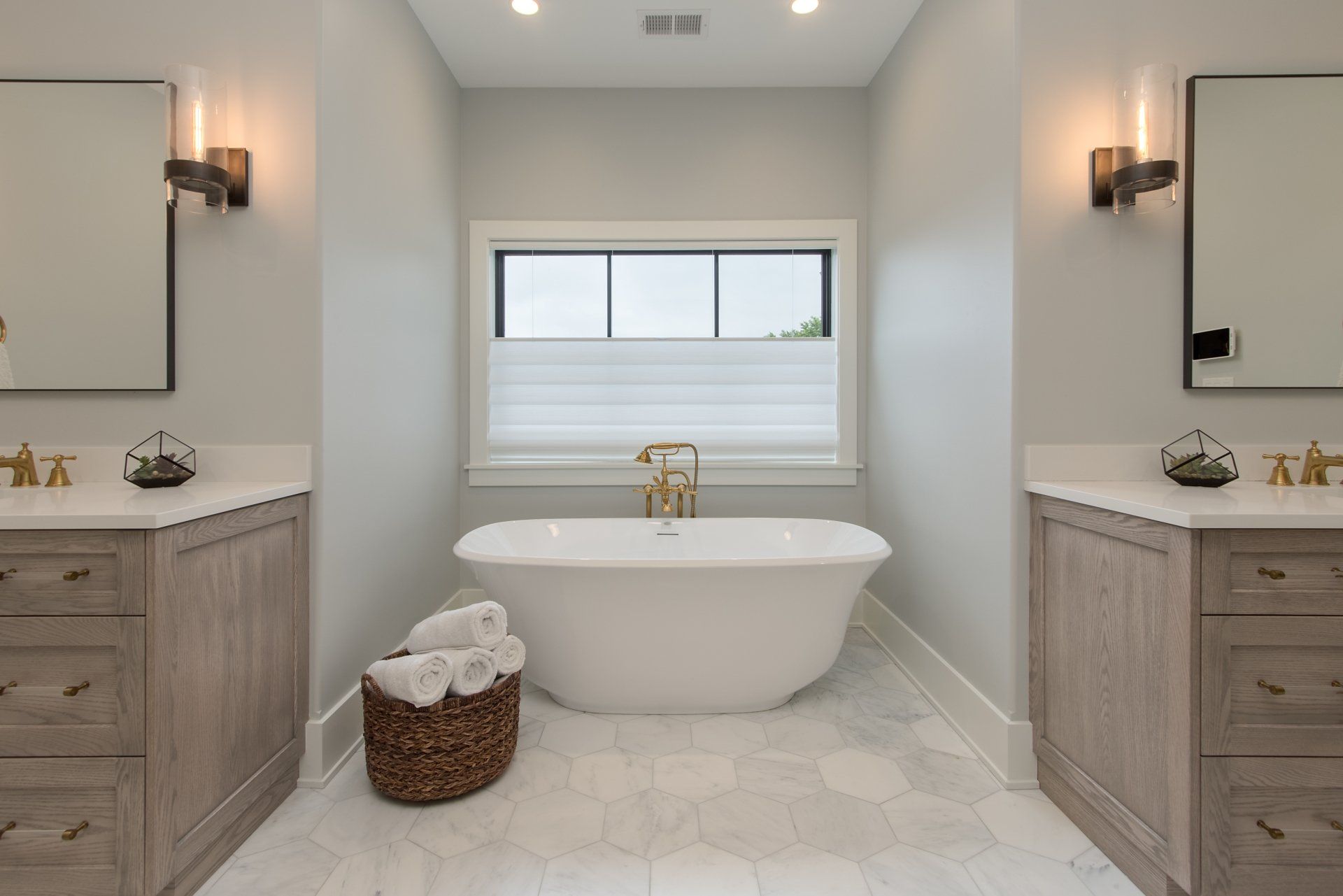A bathroom with two sinks , a tub , and a window.
