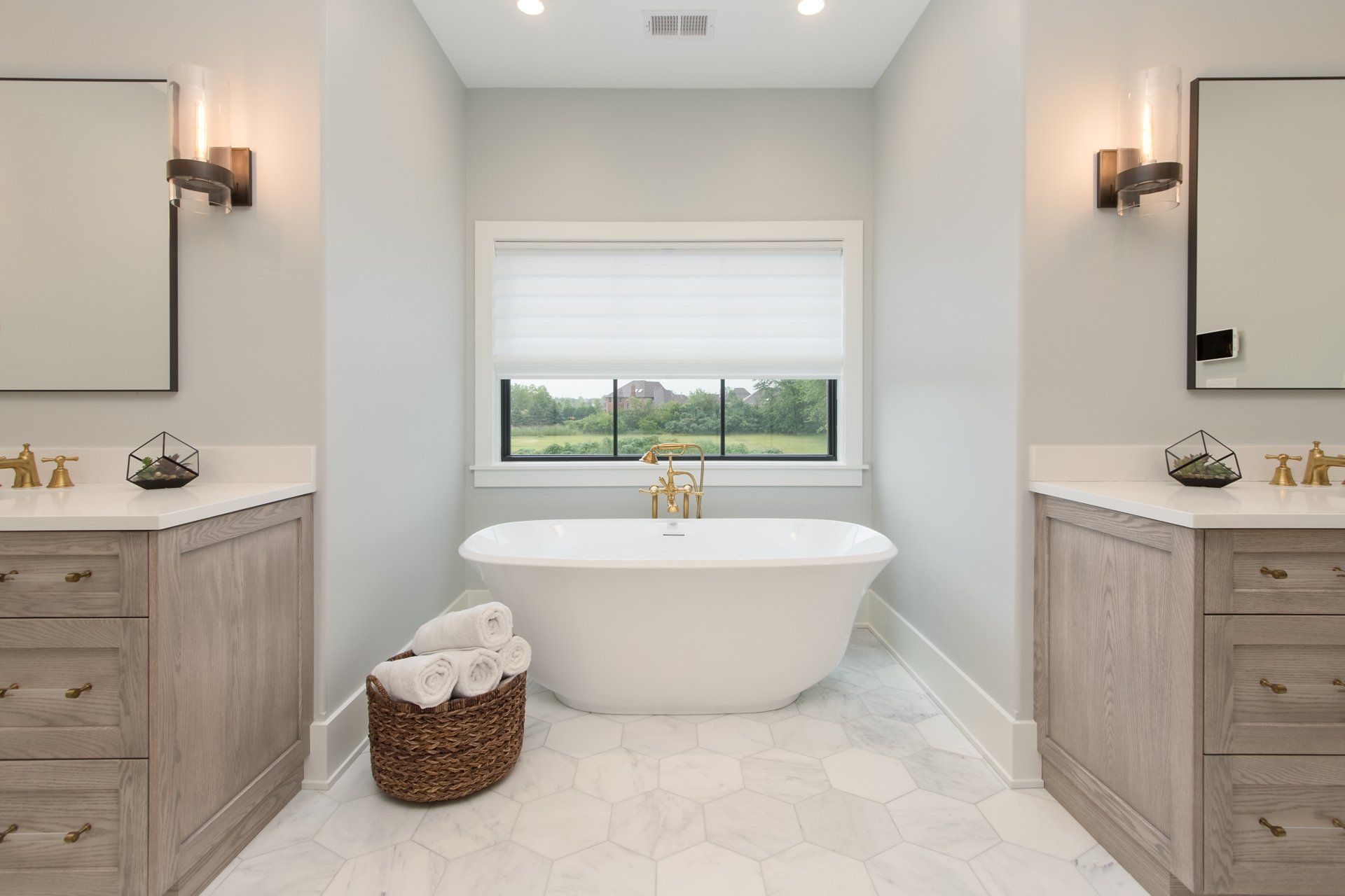 A bathroom with two sinks , a tub , and a window.