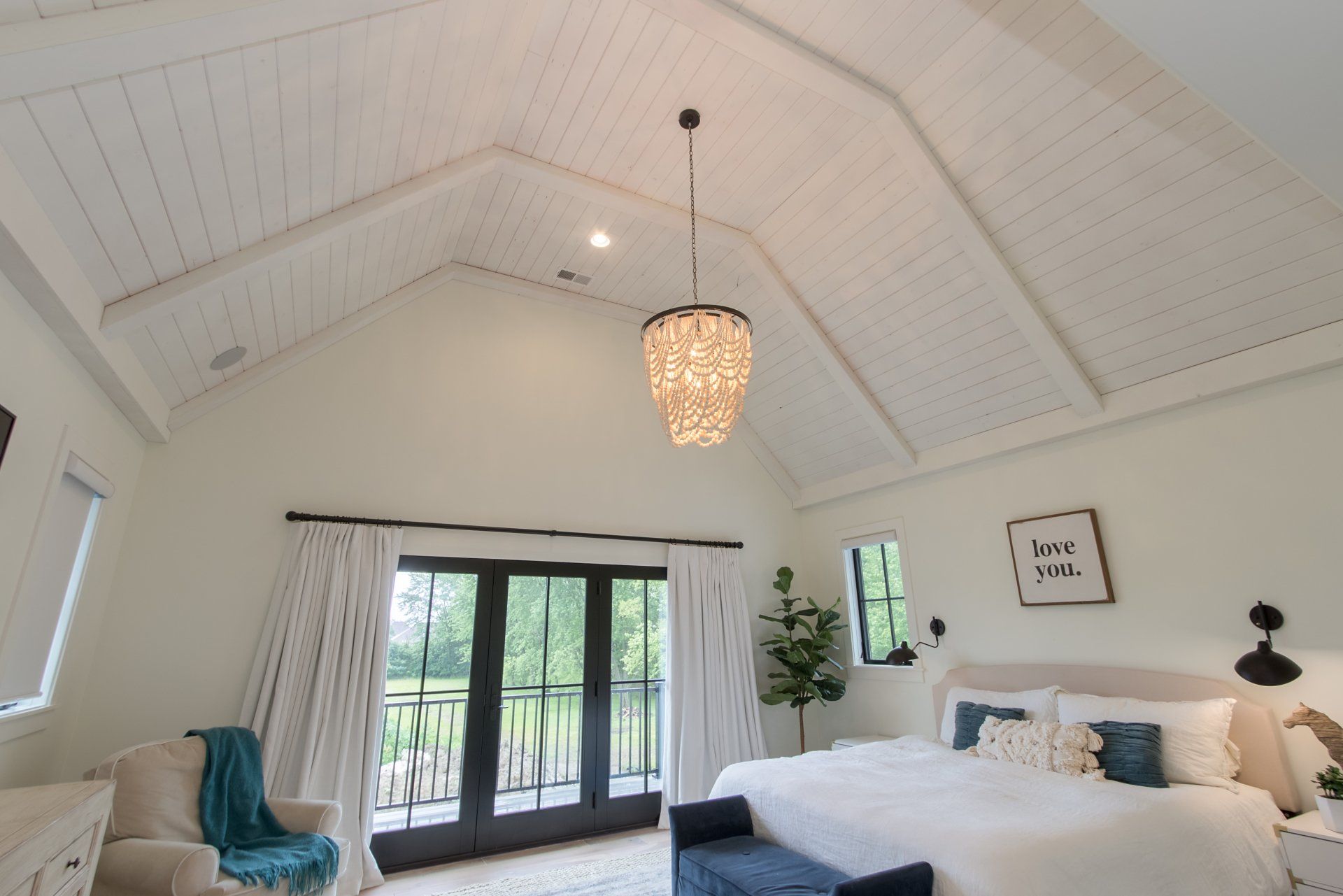 A bedroom with a large bed and a chandelier hanging from the ceiling.