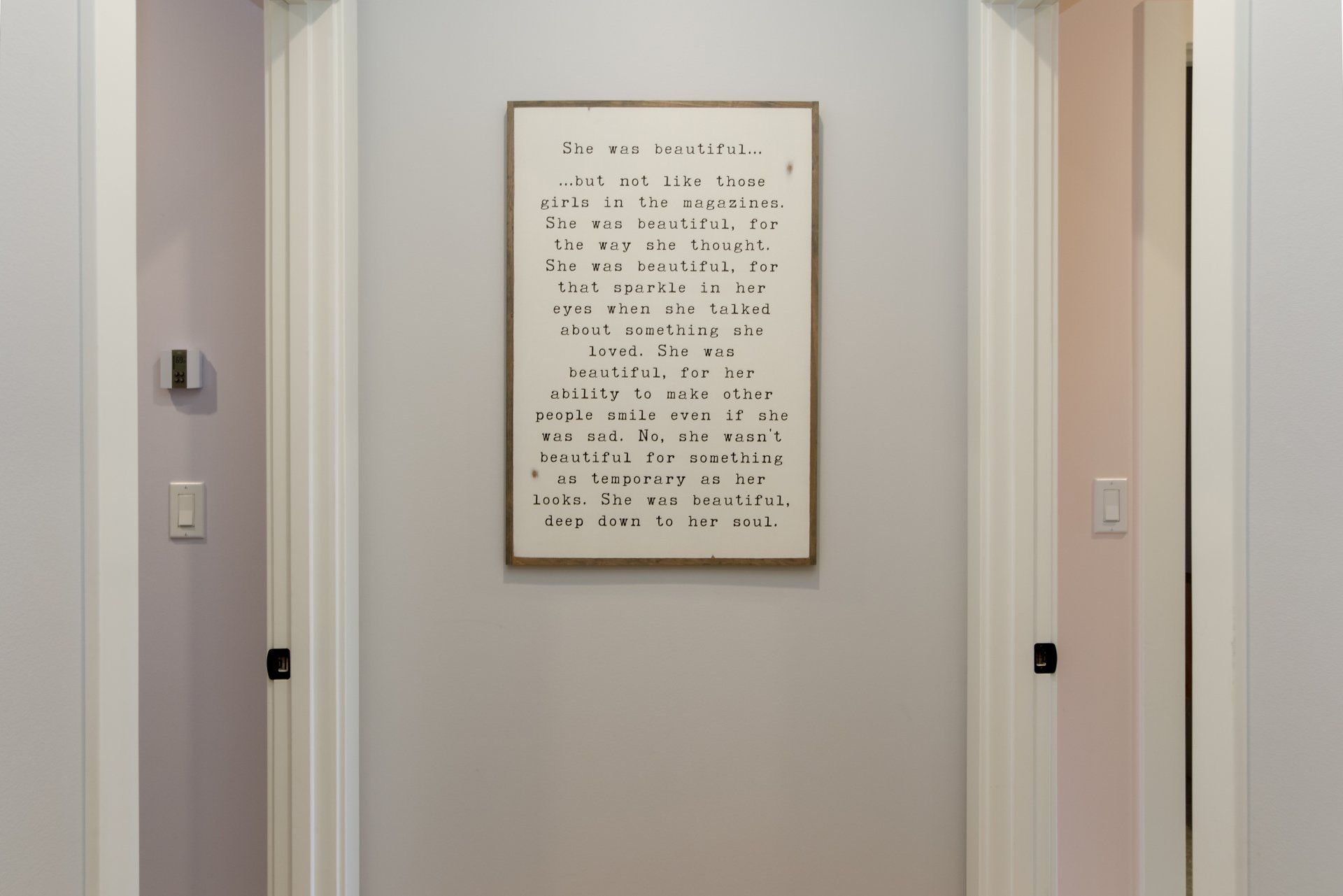 A picture of a poem is hanging on a wall in a hallway.