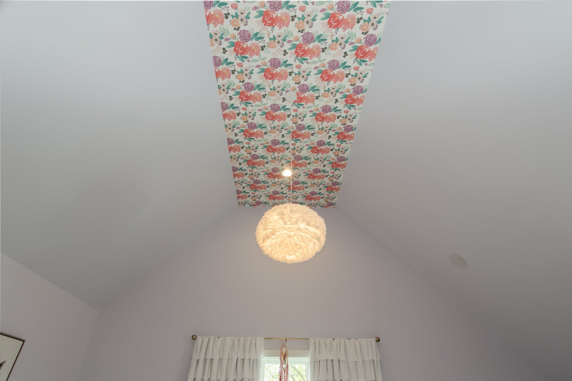 A ceiling with a floral pattern and a light hanging from it.