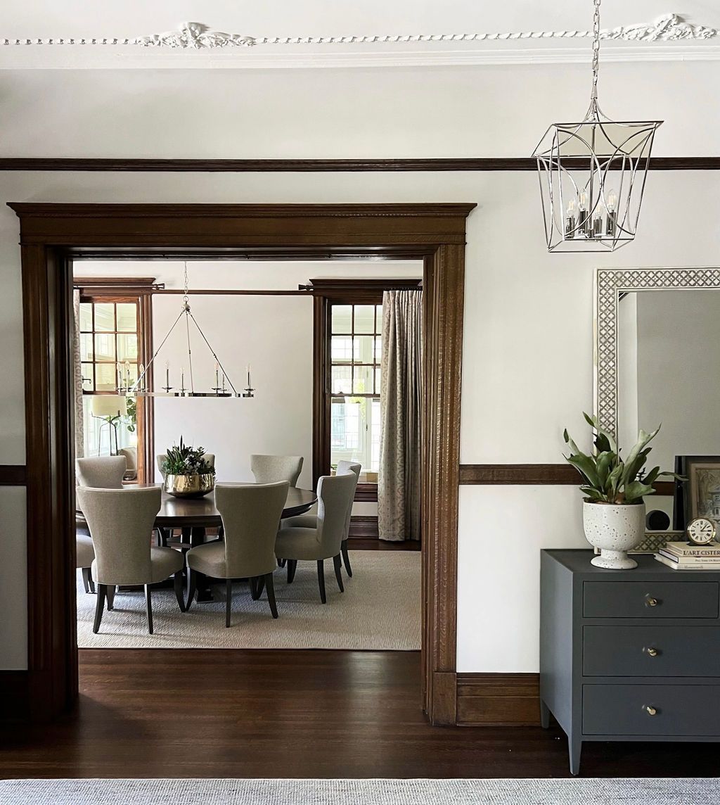 Dining room with dark wood trim, table, chairs, and chandelier; doorway to the left.