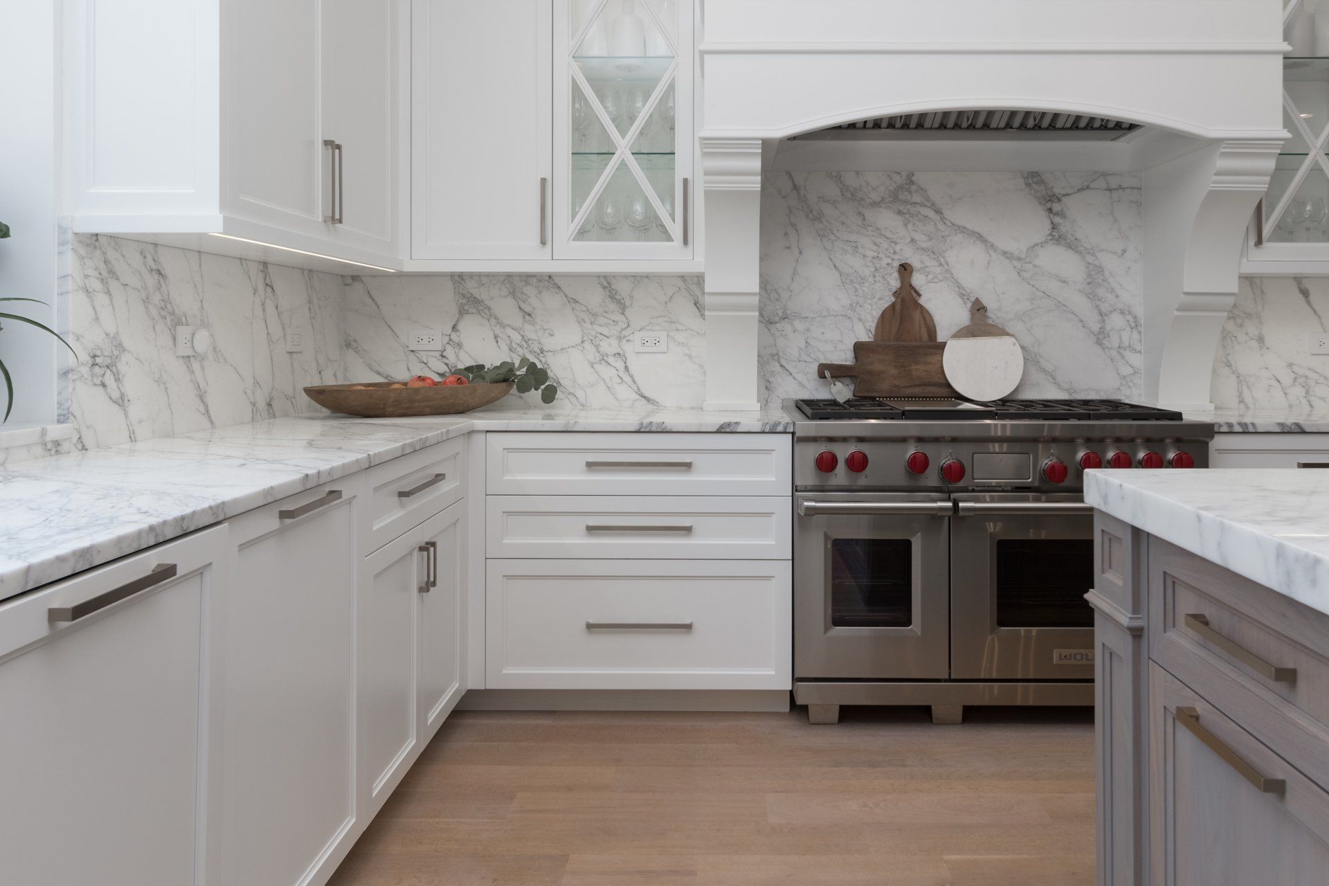 A kitchen with white cabinets , stainless steel appliances , and marble counter tops.