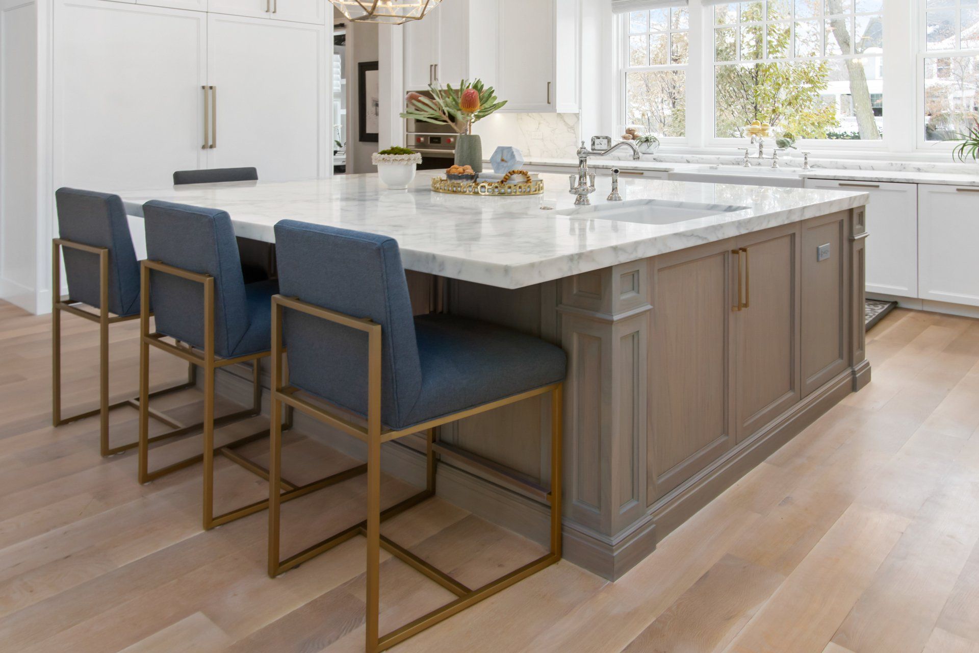 A kitchen with a large island and chairs in it.