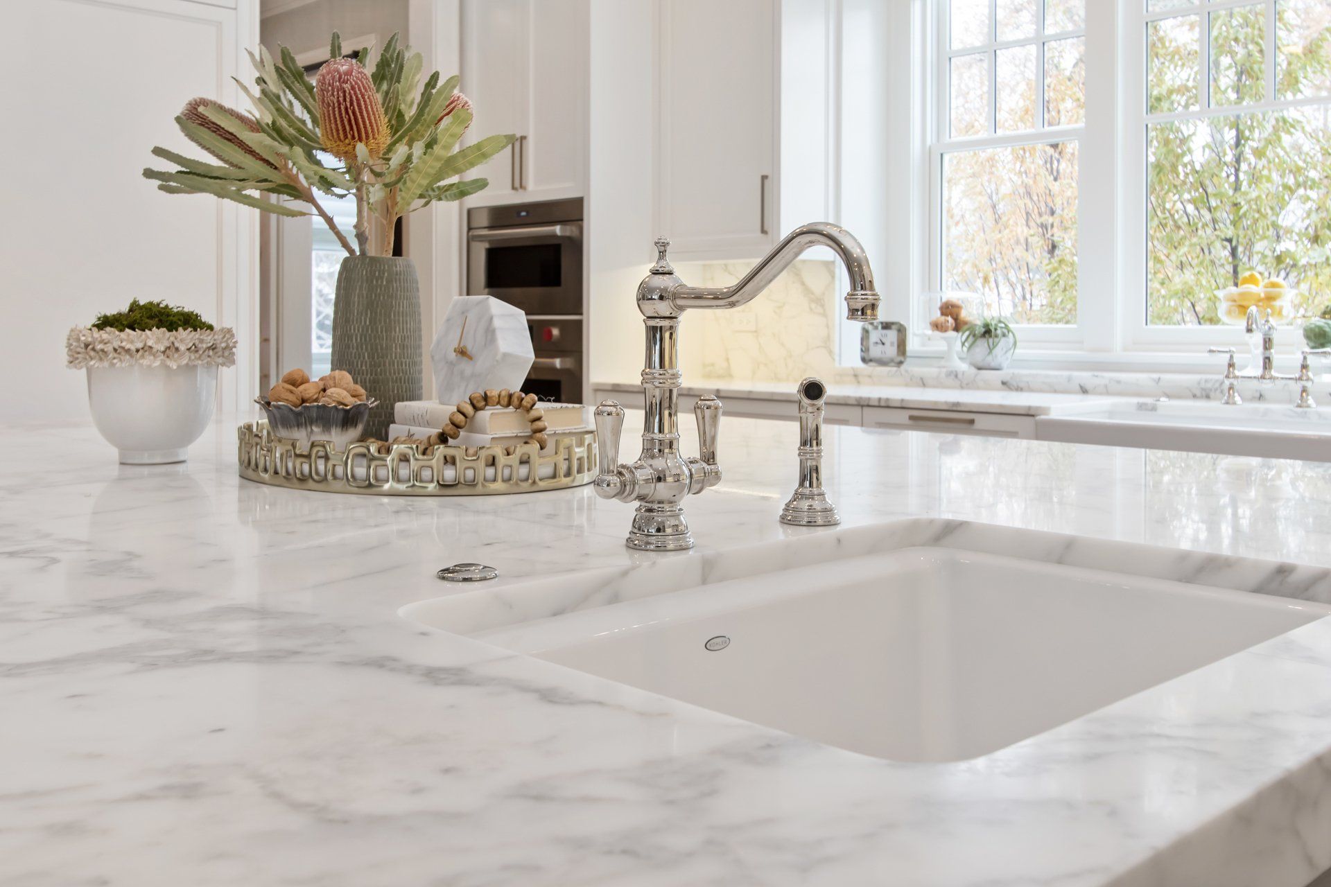 A kitchen sink with a marble counter top and a faucet.