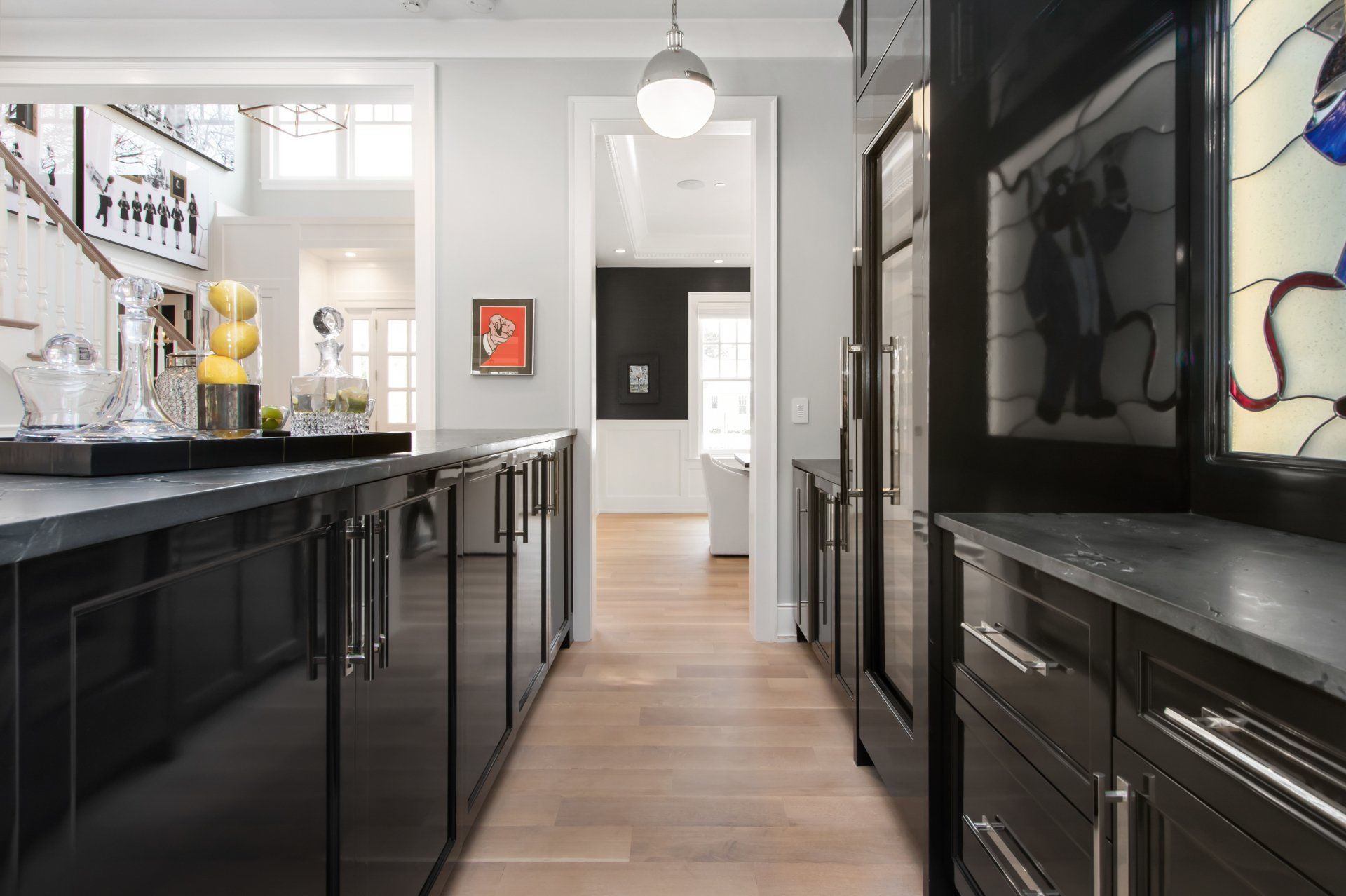 A kitchen with black cabinets and a stained glass window.