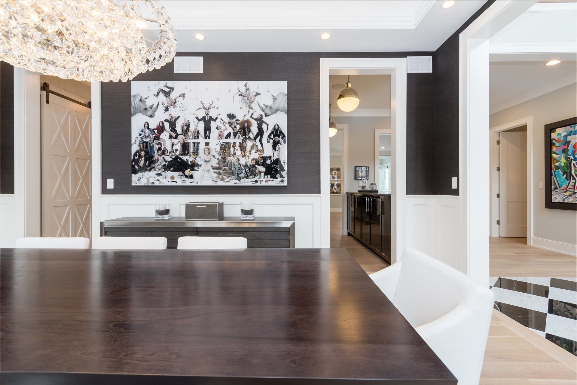 A dining room with a large painting on the wall above the table.