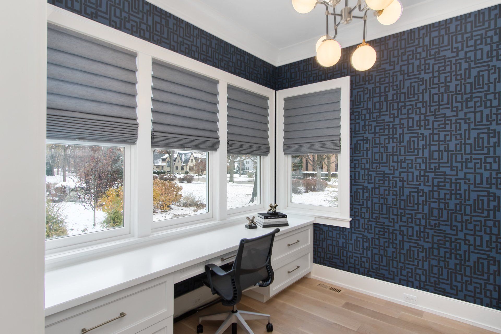 A home office with a desk , chair , and windows.
