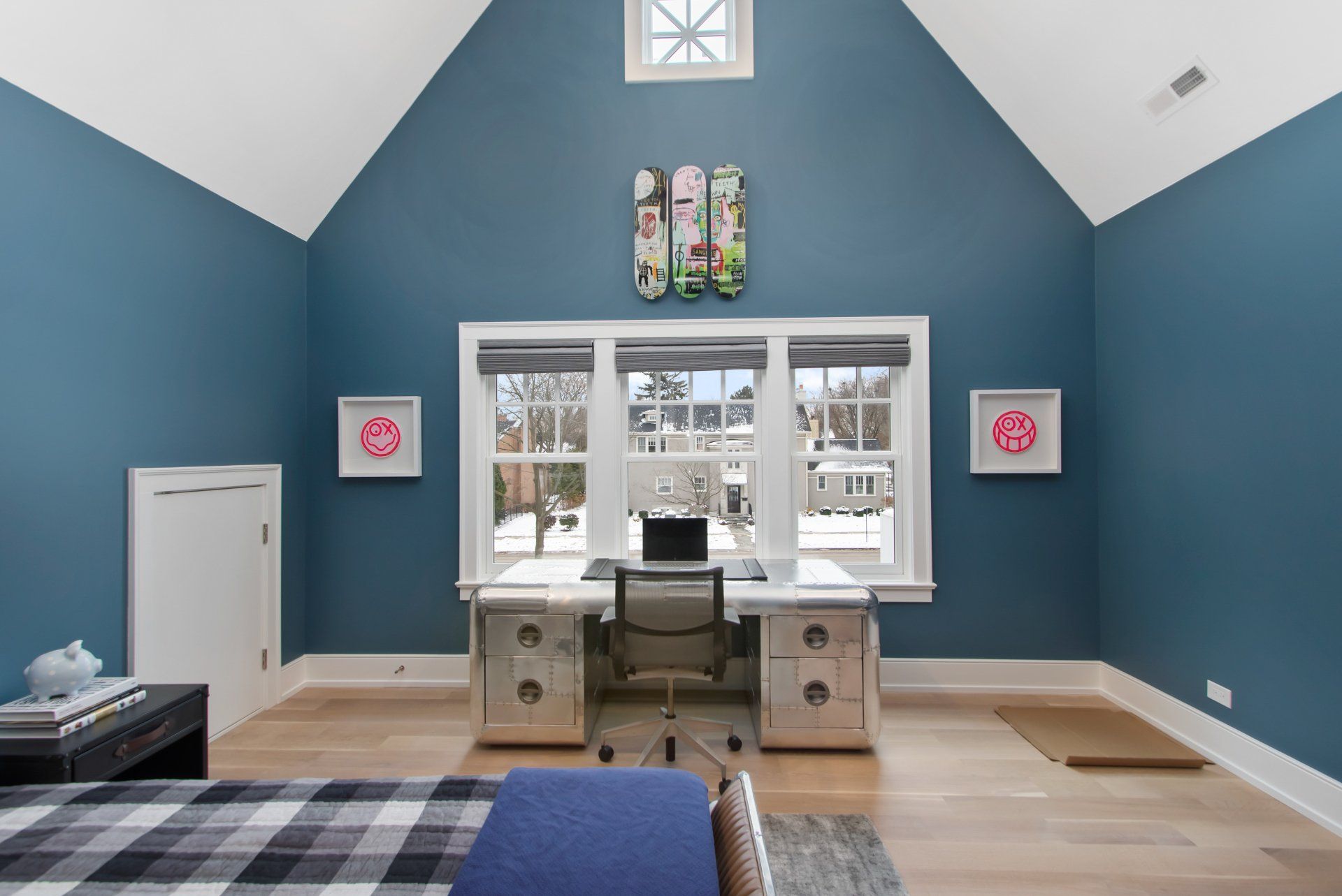 A bedroom with blue walls and a white desk with a laptop on it.