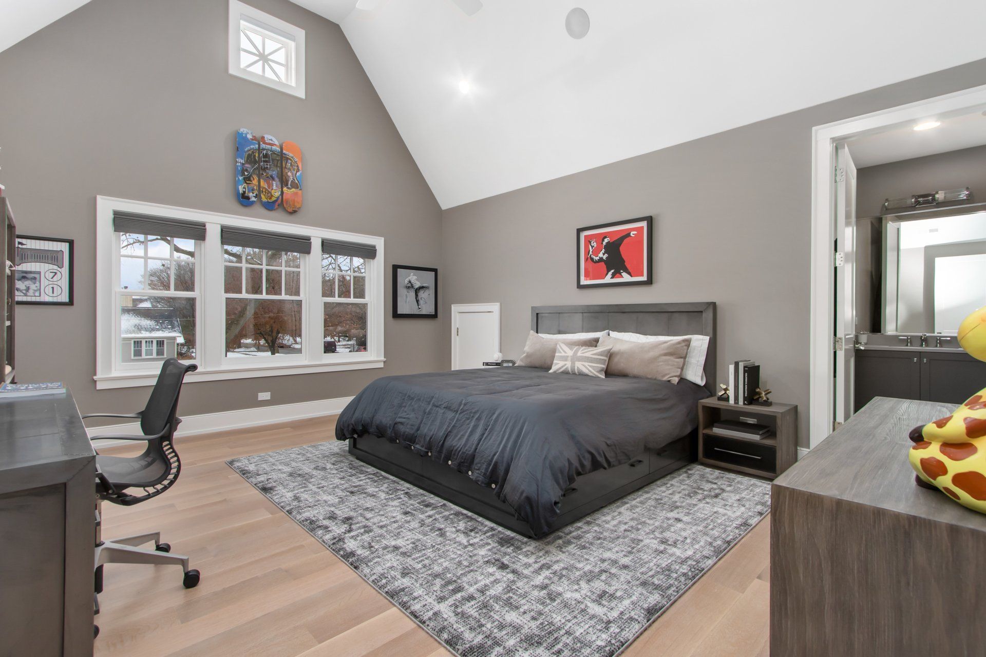 A bedroom with a king size bed , desk , chair and rug.