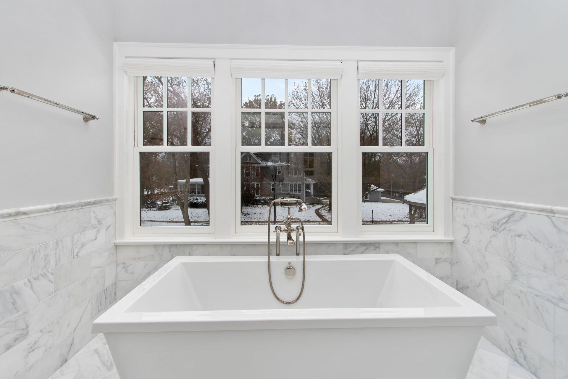 There is a bathtub in the bathroom with three windows.