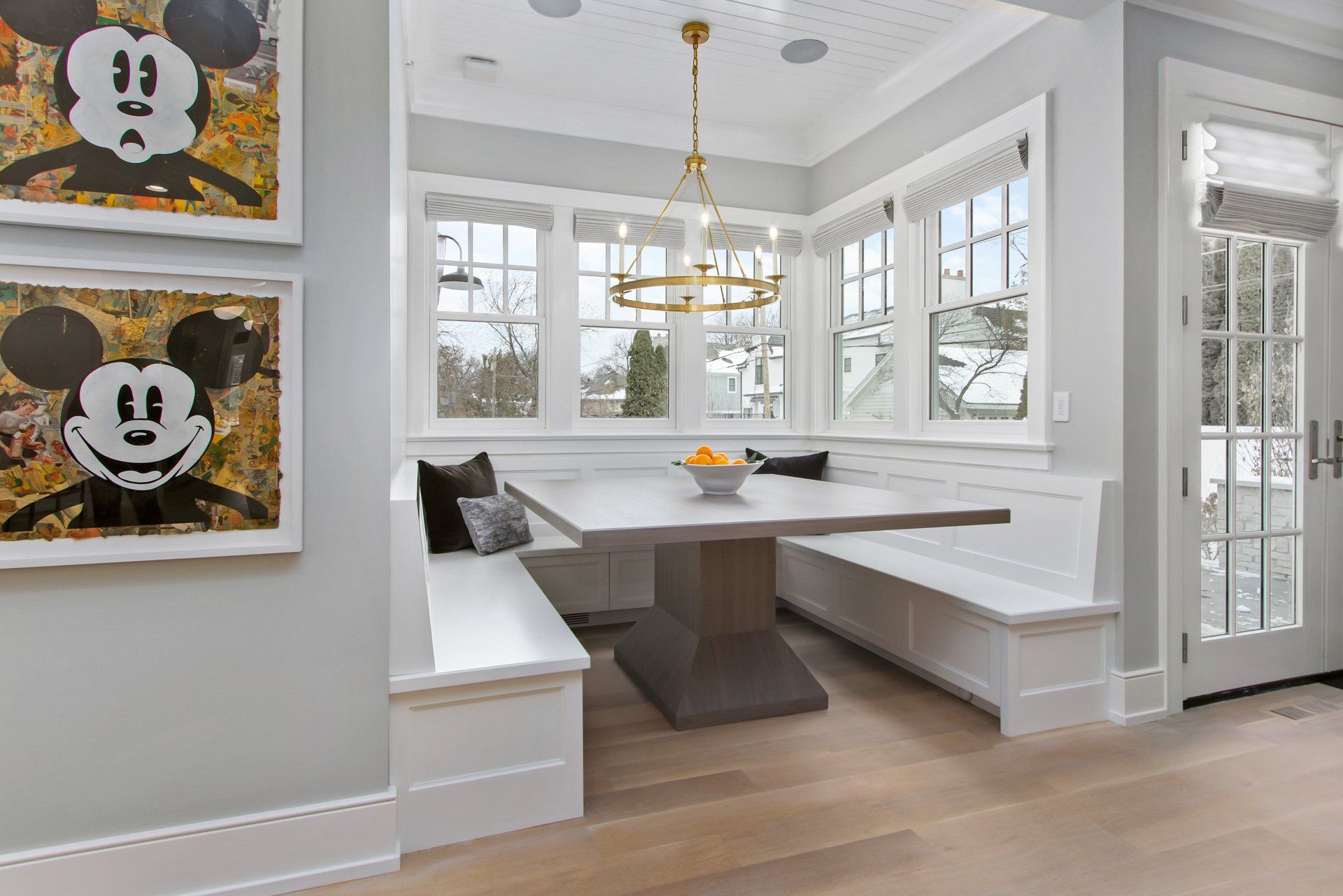 A dining room with a table and benches and a mickey mouse painting on the wall.