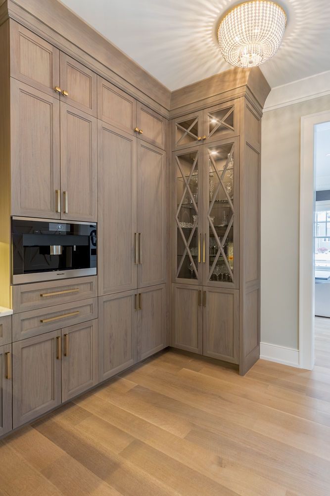 Corner kitchen cabinetry with light wood floors, built-in coffee machine, and glass-front cabinet.