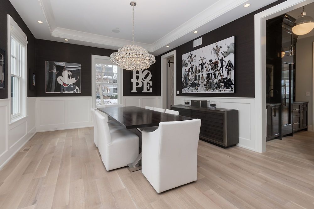 Dining room with dark walls, white trim, and a long table with white chairs.