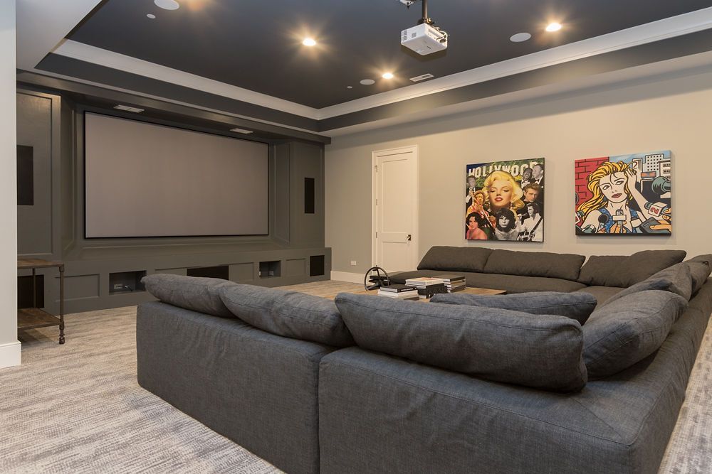 Home theater with gray sectional sofa, large screen, and colorful pop art.