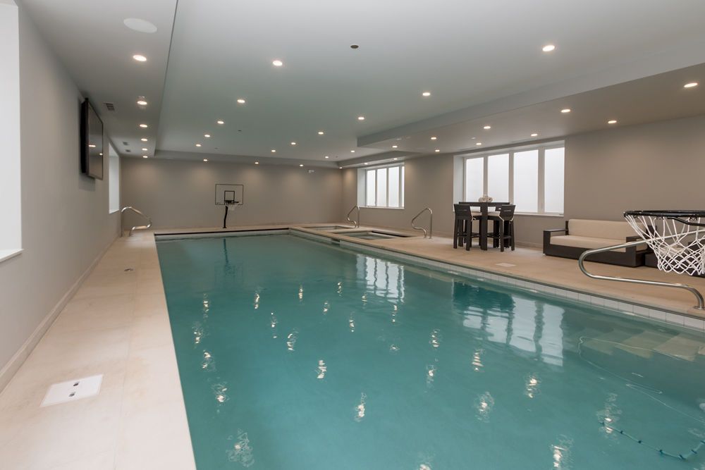 Indoor swimming pool with turquoise water, neutral walls, and seating area.