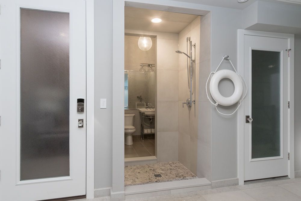 Bathroom interior with shower, sink, and toilet visible through a doorway. Two white doors flank the entrance.
