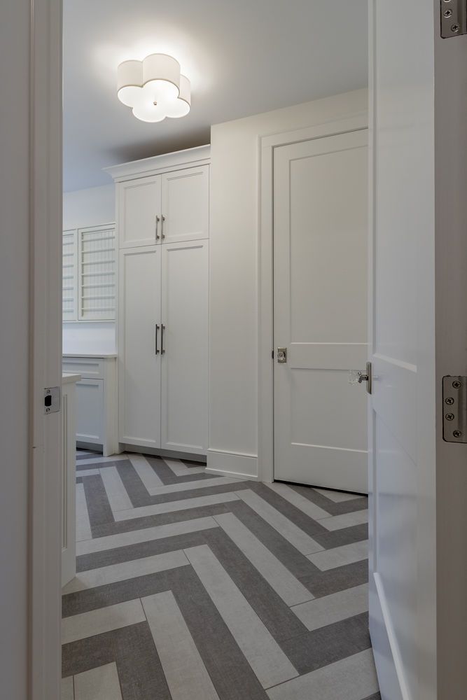 Hallway with white walls, cabinets, and a chevron patterned gray and white floor.