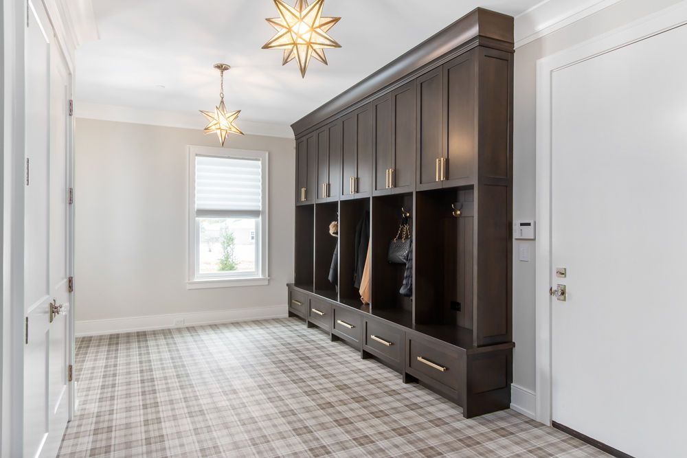 Hallway with built-in dark wood lockers, plaid carpet, and starburst light fixtures.