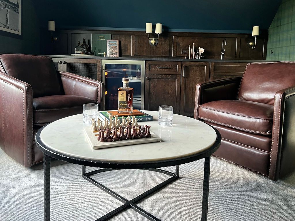 Cozy den with leather chairs, marble coffee table, bar, and chess set.