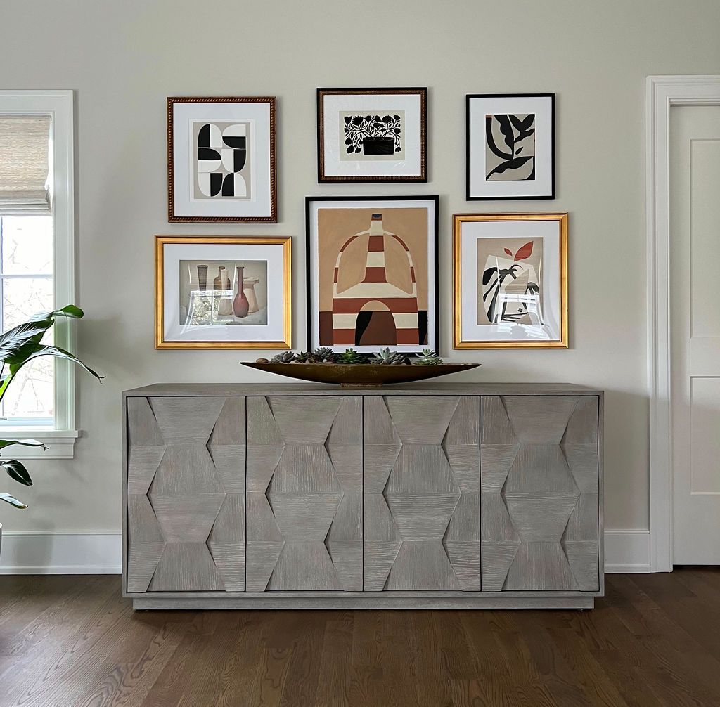 A gray cabinet with abstract art above, displayed on a light gray wall. Dark wood floor.