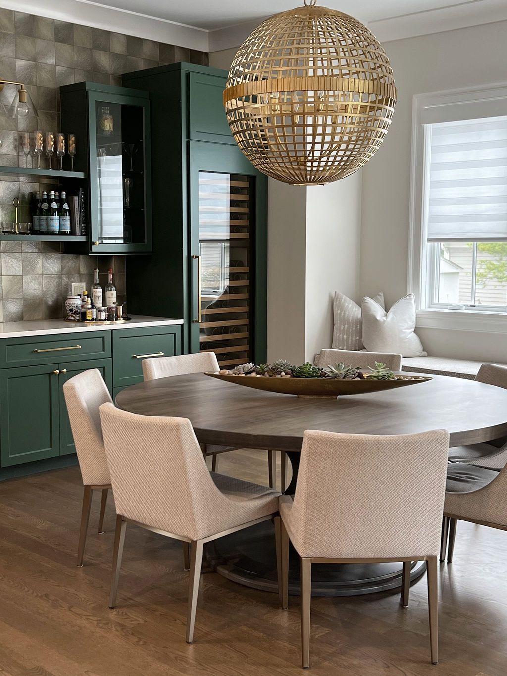 Dining room with green cabinetry, a round table, and a gold orb light fixture.