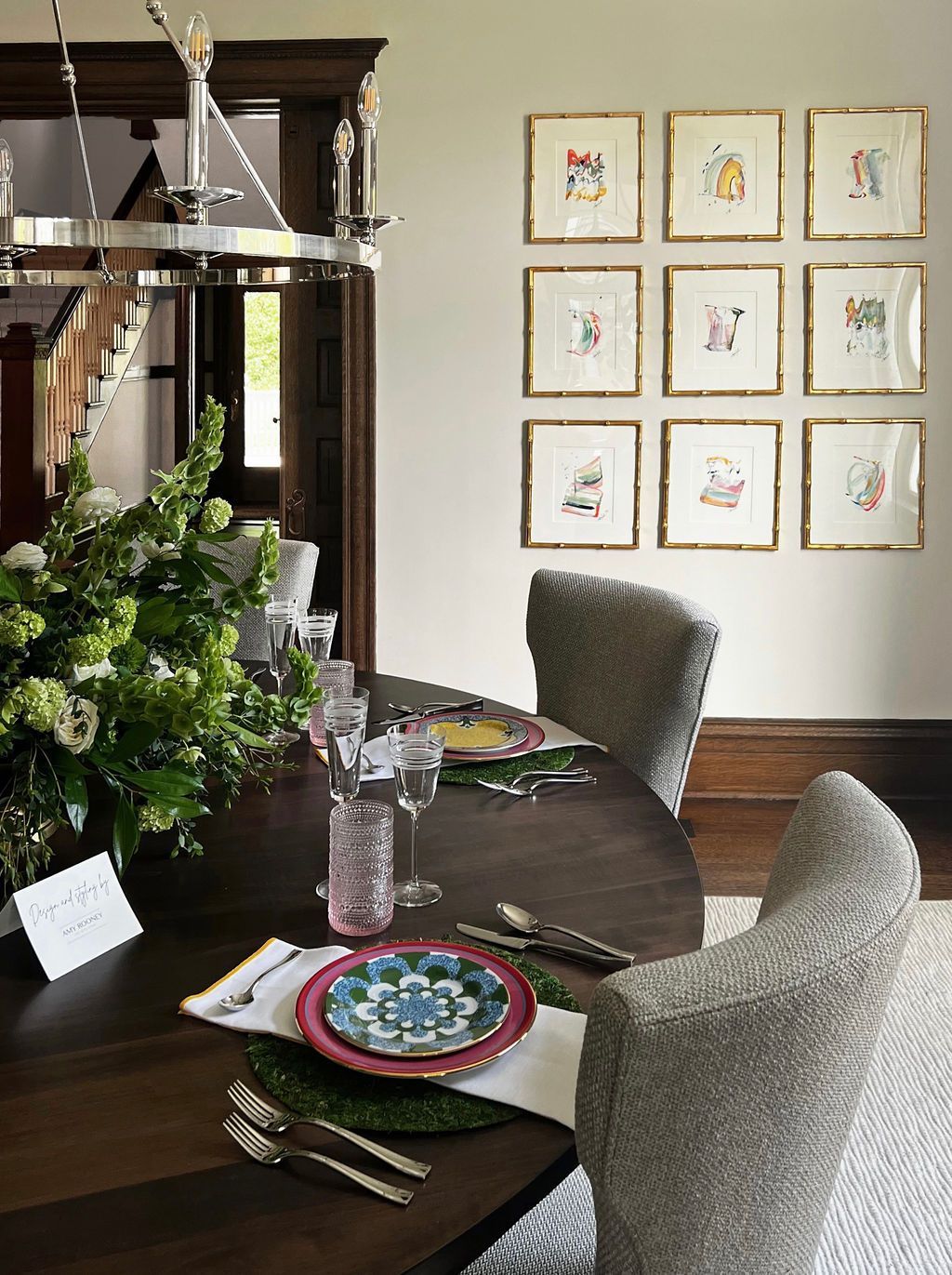 Dining room with a table set for guests, art on the wall, and upholstered chairs.