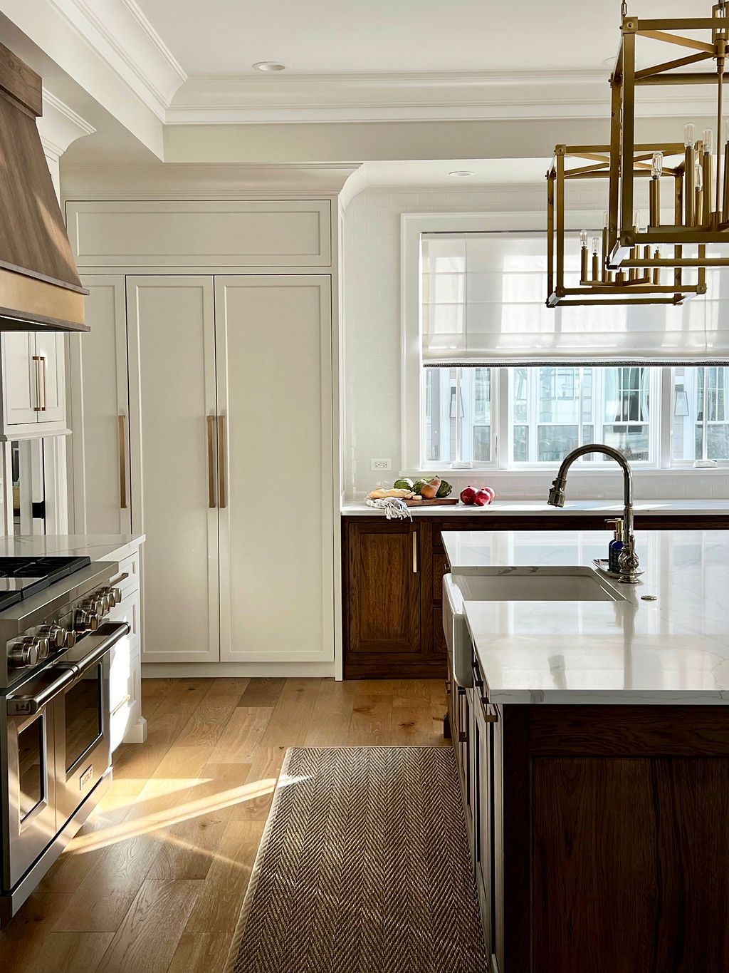 Elegant kitchen with white and dark wood cabinetry, stainless steel appliances, and a rectangular rug.