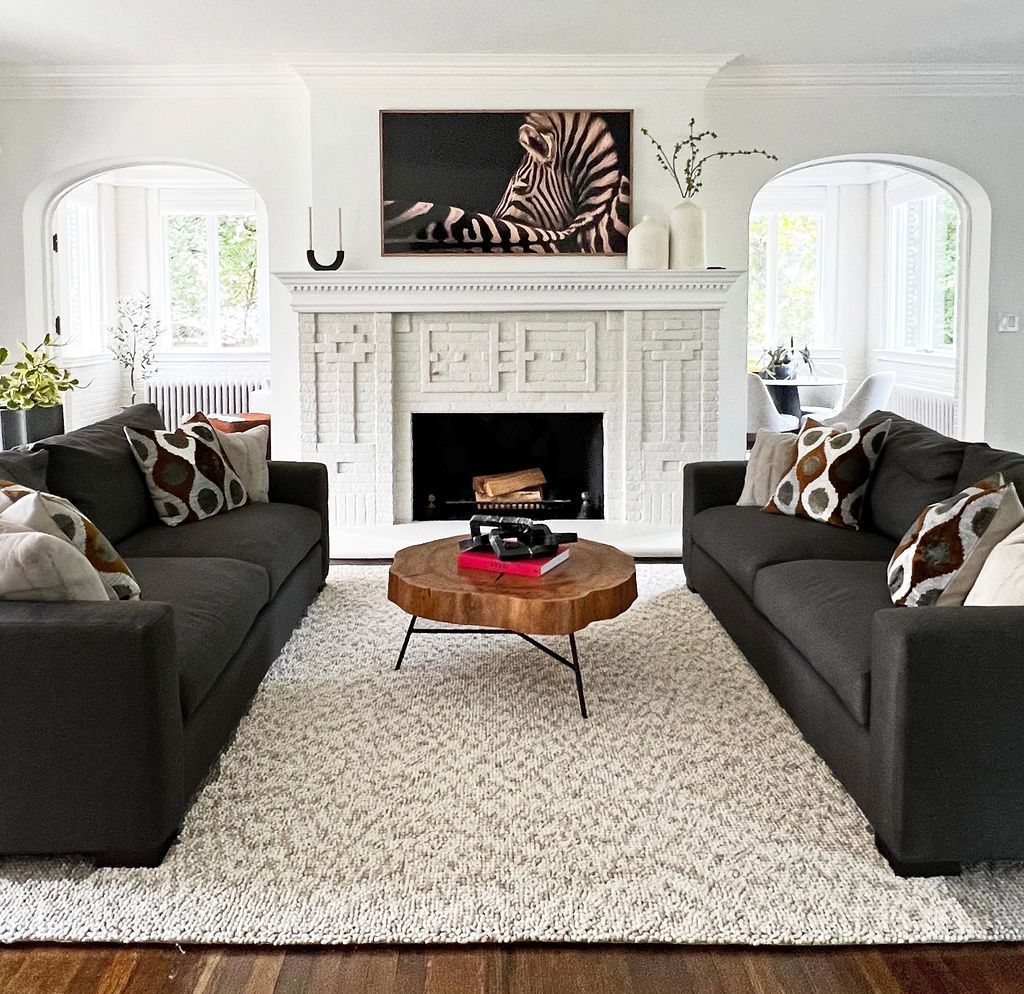 Living room with two dark gray sofas facing each other, white fireplace, and a zebra print above it.