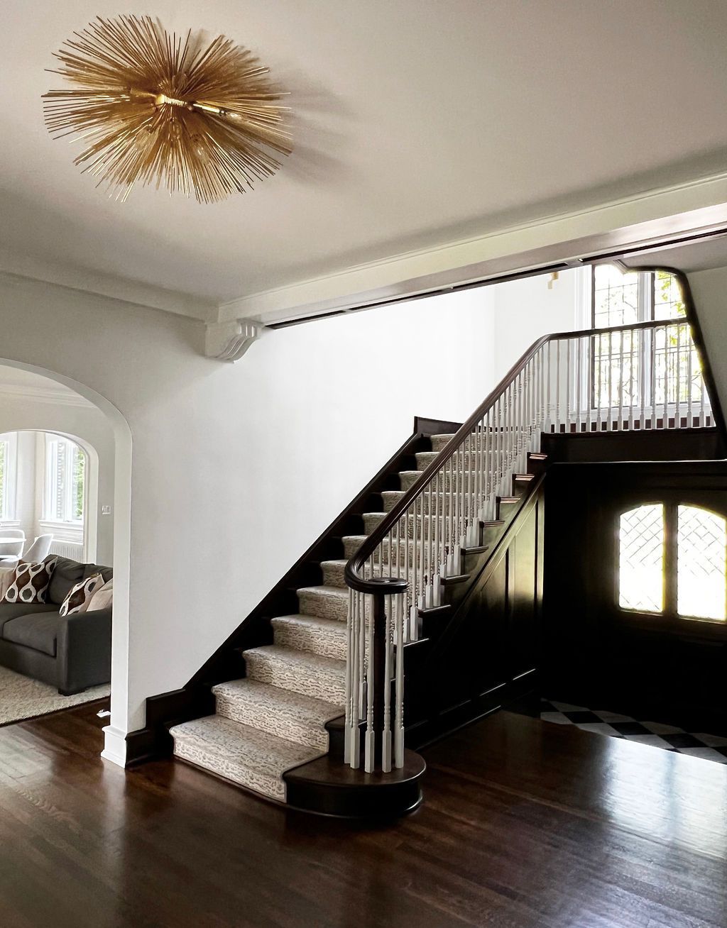 A grand entry hall with a staircase and a decorative sputnik ceiling light.