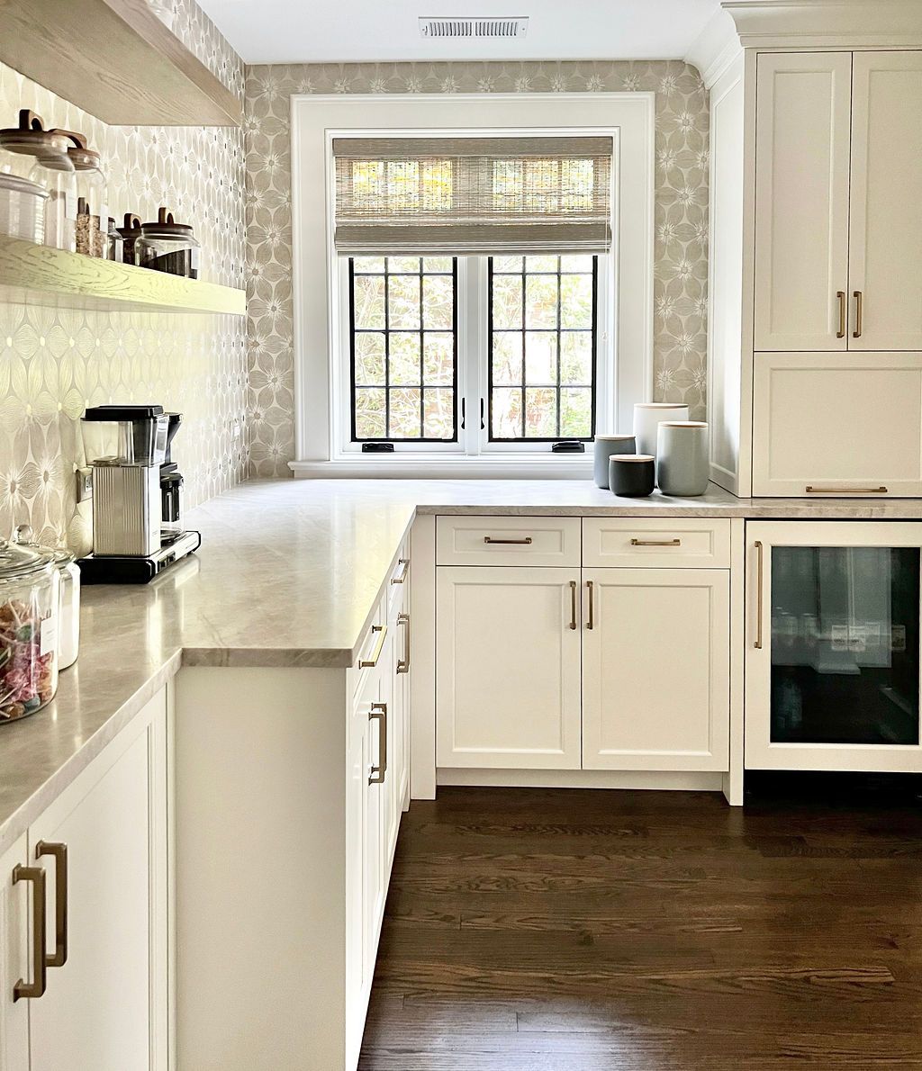 White kitchen with light countertops, dark wood floor, and window with a shade.