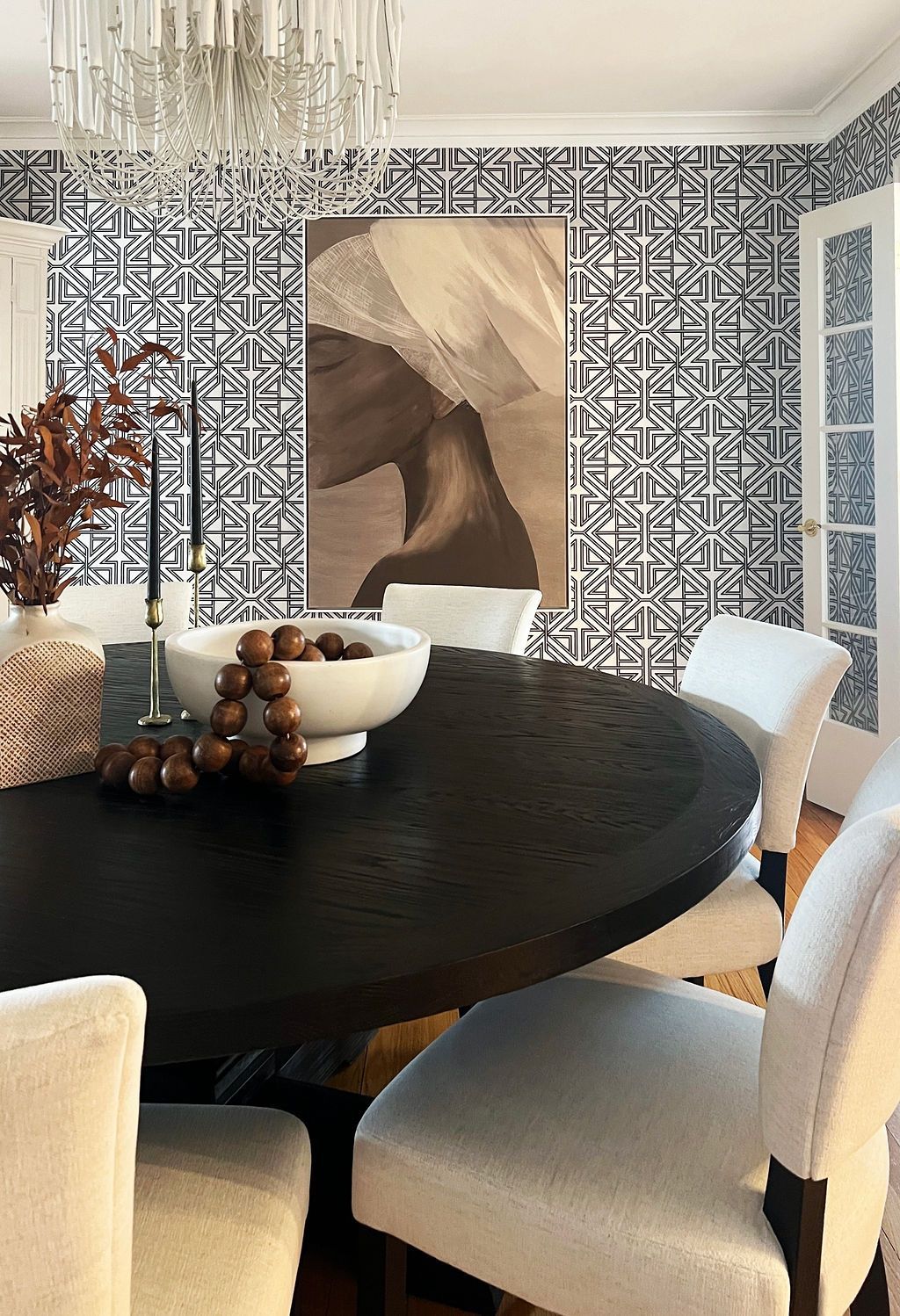 Formal dining room with black table, patterned wallpaper, and abstract art.