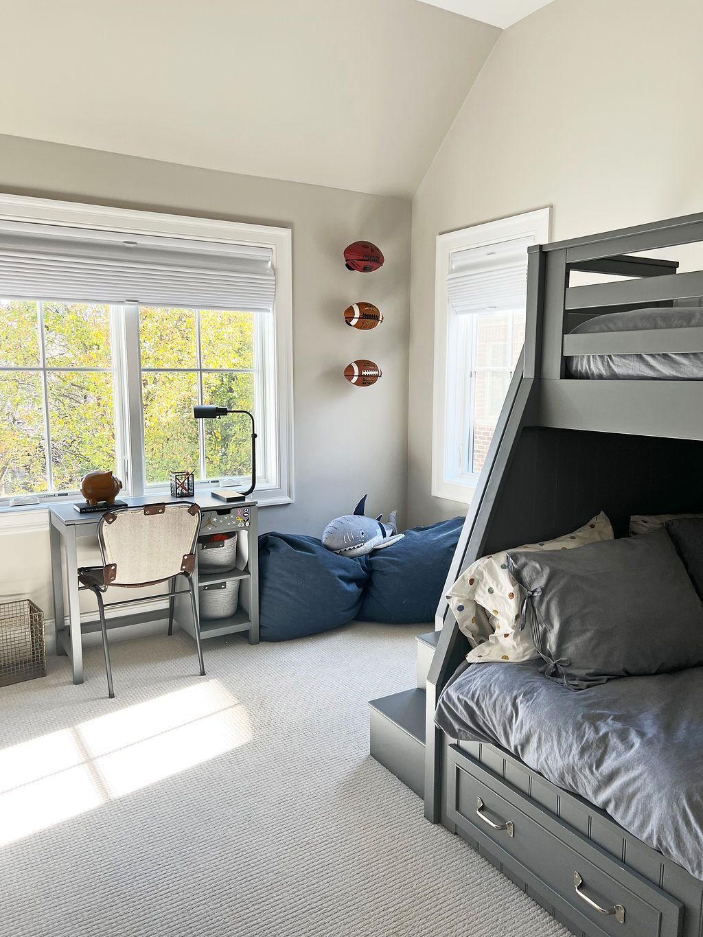 Bedroom with bunk bed, desk, and beanbag chairs. Gray walls, white trim, and light carpet.
