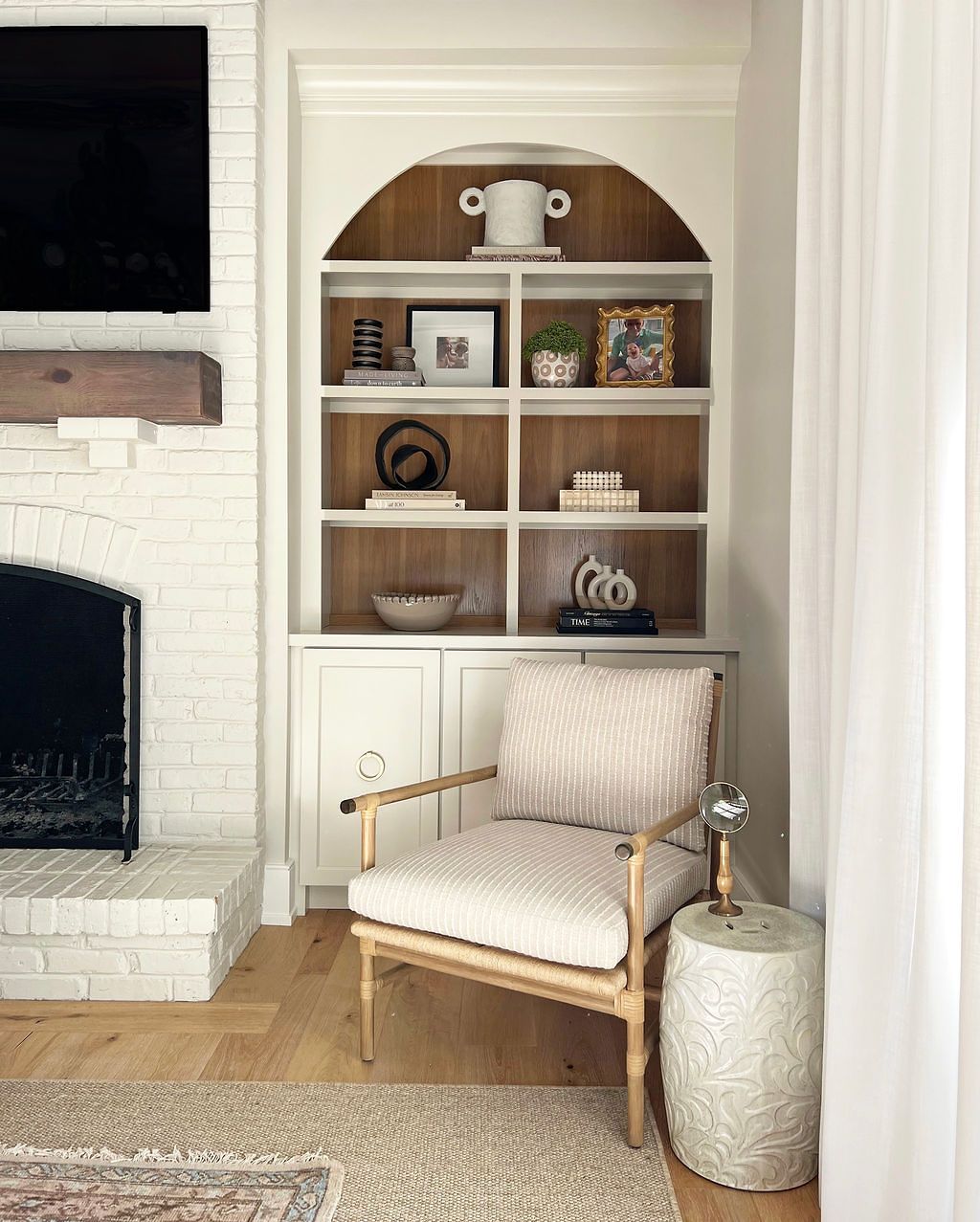 Built-in white bookshelf in a room with a fireplace, chair, and rug.