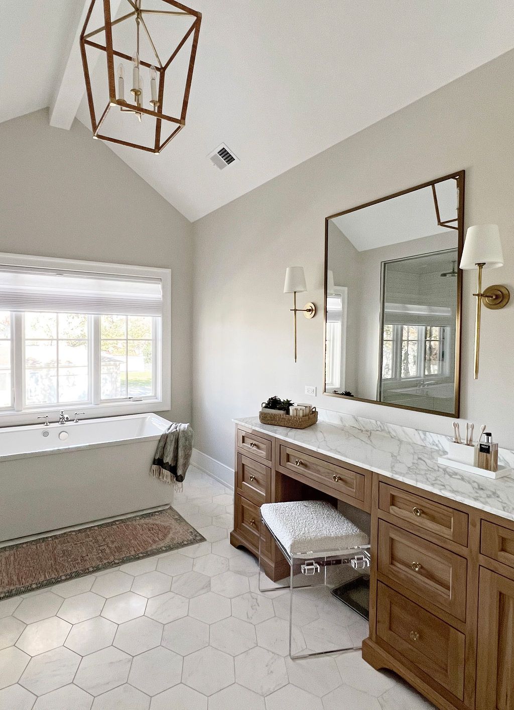 Bathroom with a wooden vanity, a large mirror, and a white soaking tub.