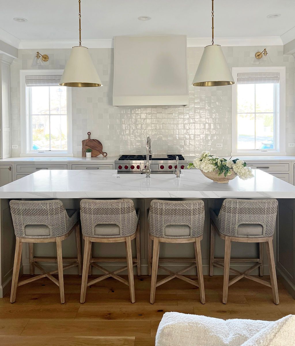 Kitchen with a white marble island, tile backsplash, and four patterned bar stools.