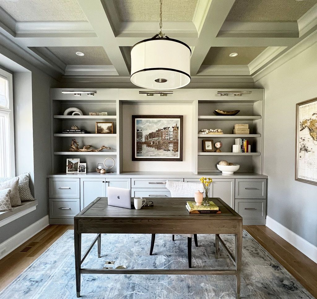 Gray home office with built-in bookshelves, a desk, a rug, a window seat, and a decorative ceiling.
