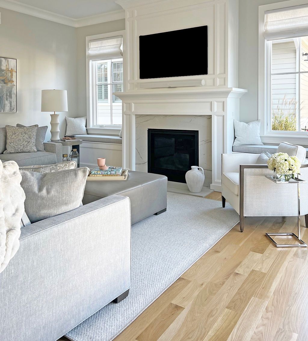 Living room with fireplace, TV, light gray furniture, white trim, and hardwood floors.