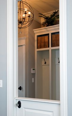 A white door is open to a hallway with a chandelier hanging from the ceiling.