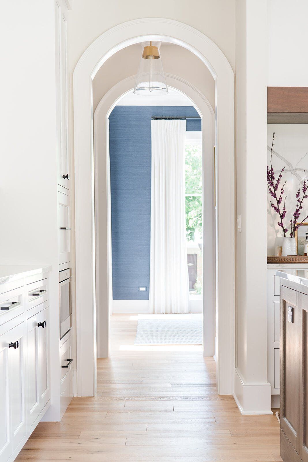 A kitchen with a long hallway leading to a living room.