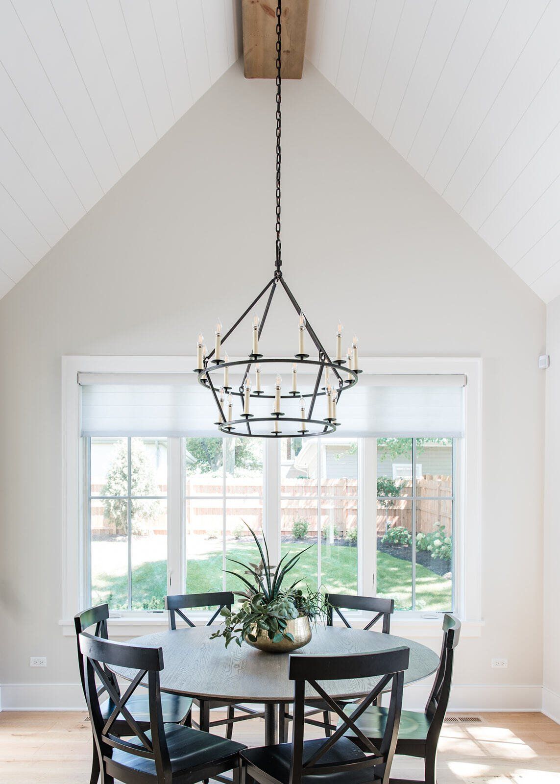 A dining room with a table and chairs and a chandelier hanging from the ceiling.