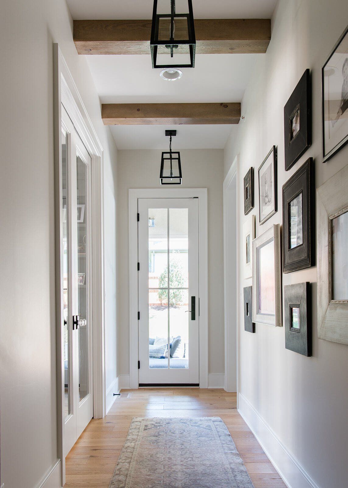 A long hallway with a white door and wooden beams.