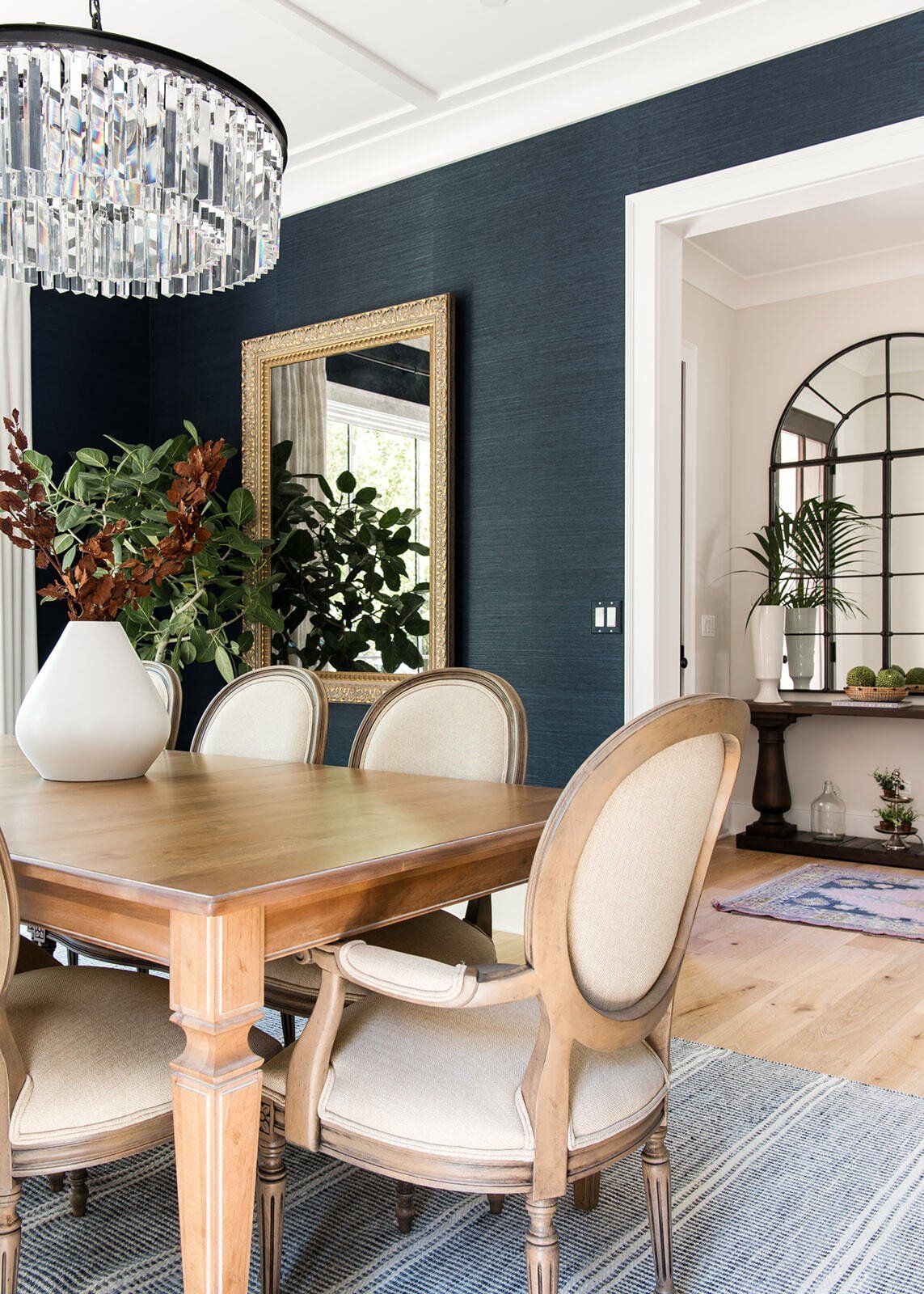 A dining room with a wooden table and chairs and a chandelier.