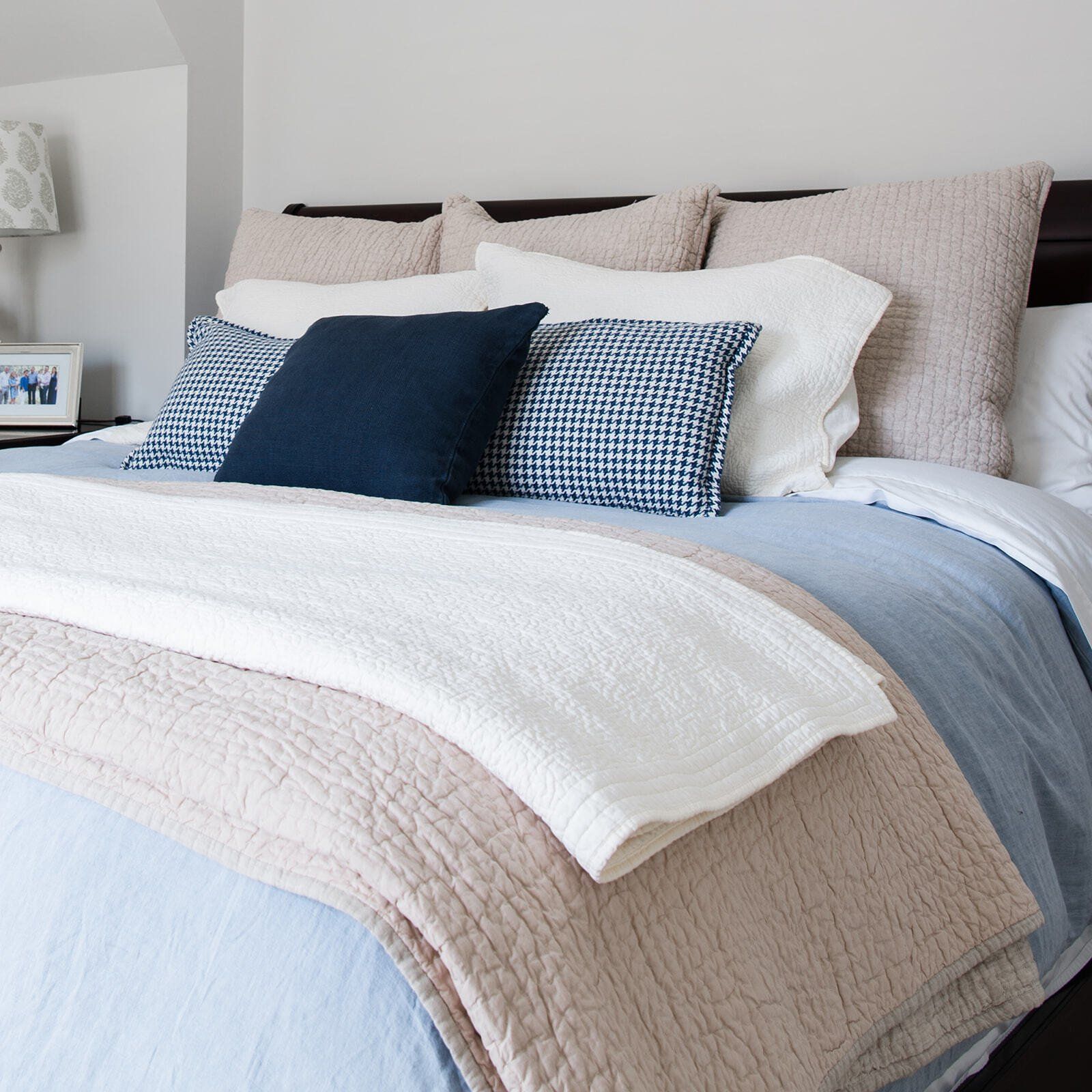 A bed with blue and white pillows and a white blanket