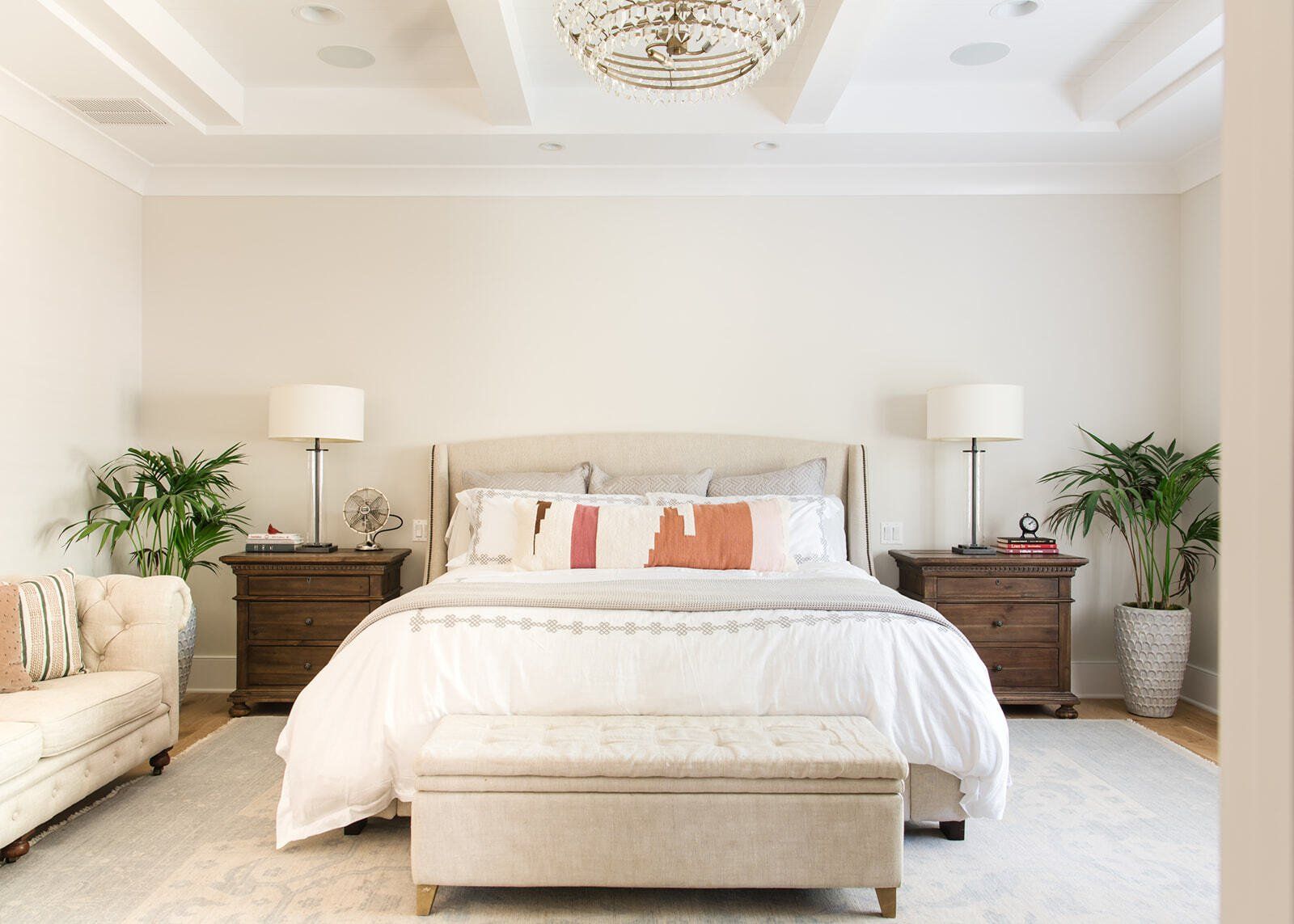 A bedroom with a bed , nightstands , a couch and a bench.