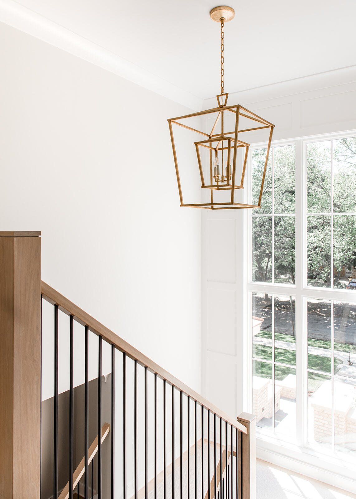 A staircase with a lantern hanging from the ceiling and a window.