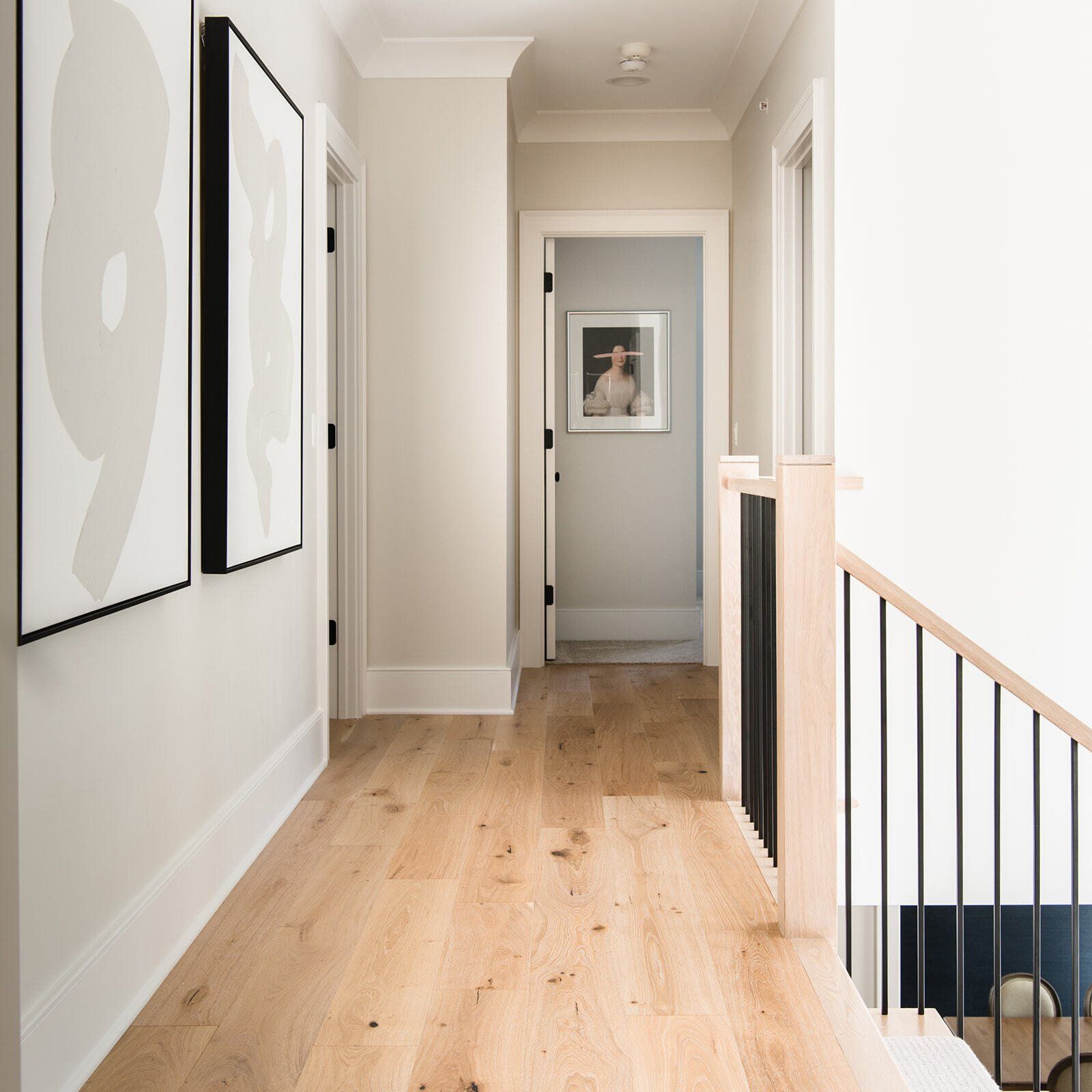 A hallway with a wooden floor and stairs leading up to the second floor.