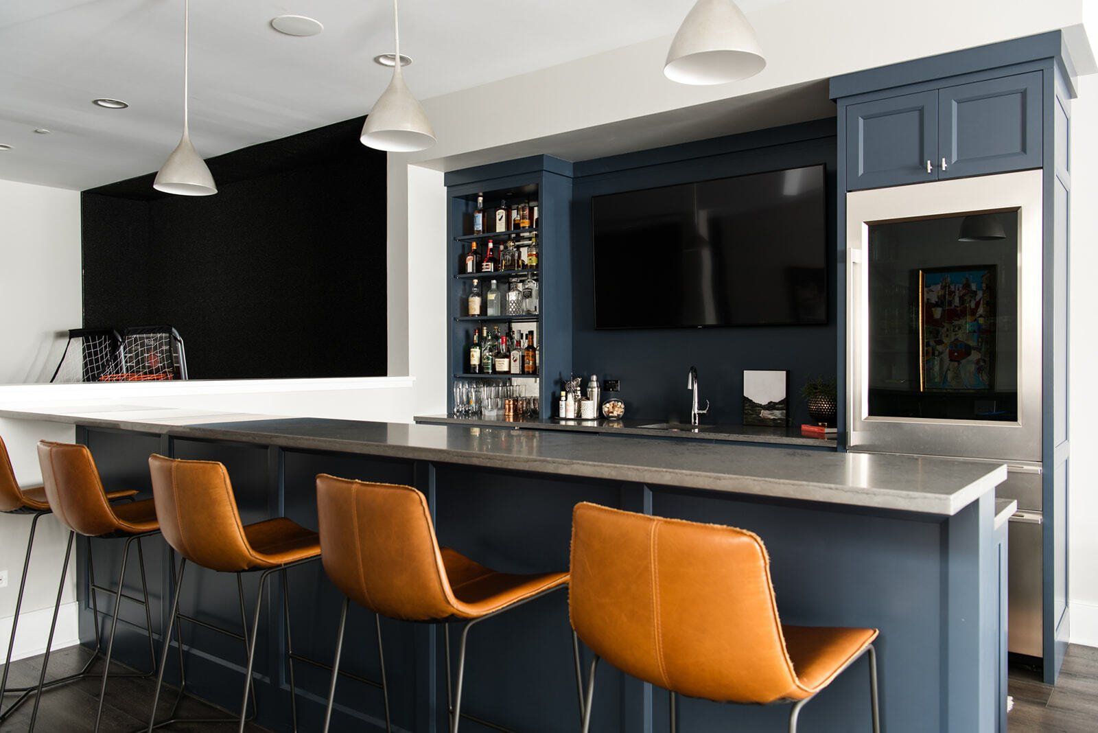 A kitchen with a bar , chairs and a television.